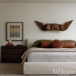Bedroom with carved angel wall decor, bed, and magazine cover.