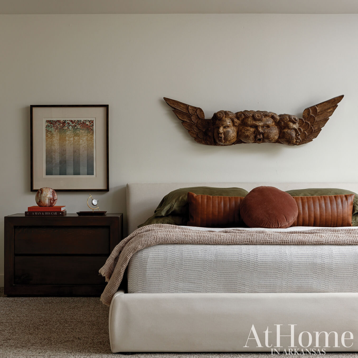 Bedroom with carved angel wall decor, bed, and magazine cover.