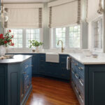 Blue kitchen island with white marble countertops and brass hardware.