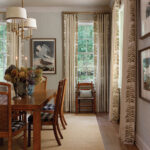 Dining room with patterned wallpaper, curtains, and a wooden table.