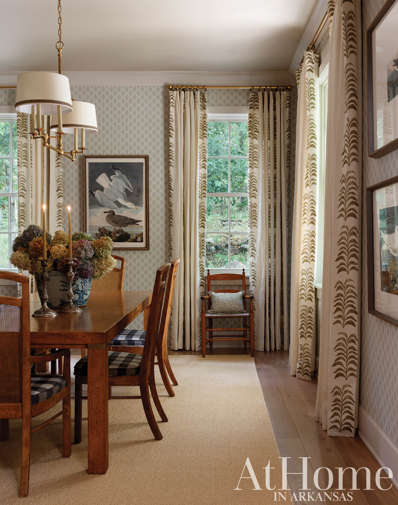 Dining room with patterned wallpaper, curtains, and a wooden table.
