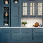 Dark blue cabinetry with glass-fronted cabinets and marble countertop.