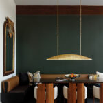 Gold pendant light hangs above a wooden dining table.
