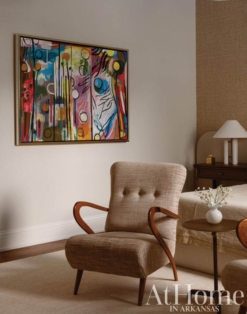 Abstract painting above a beige armchair and side table in a neutral-toned room.