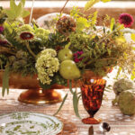 Floral centerpiece on a patterned table with tableware.