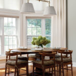 Round dining table with wooden chairs and linen drapes.