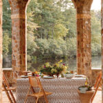Stone archway with table and chairs overlooking a river.