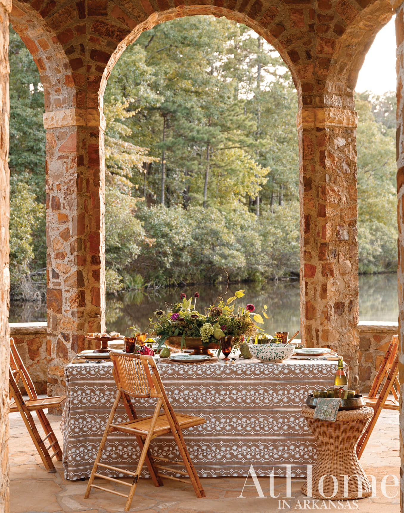 Stone archway with table and chairs overlooking a river.