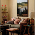 Living room with framed landscape painting, patterned sofa, and side table.