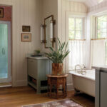 White bathroom with a vintage tub, marble sink, and wood flooring.