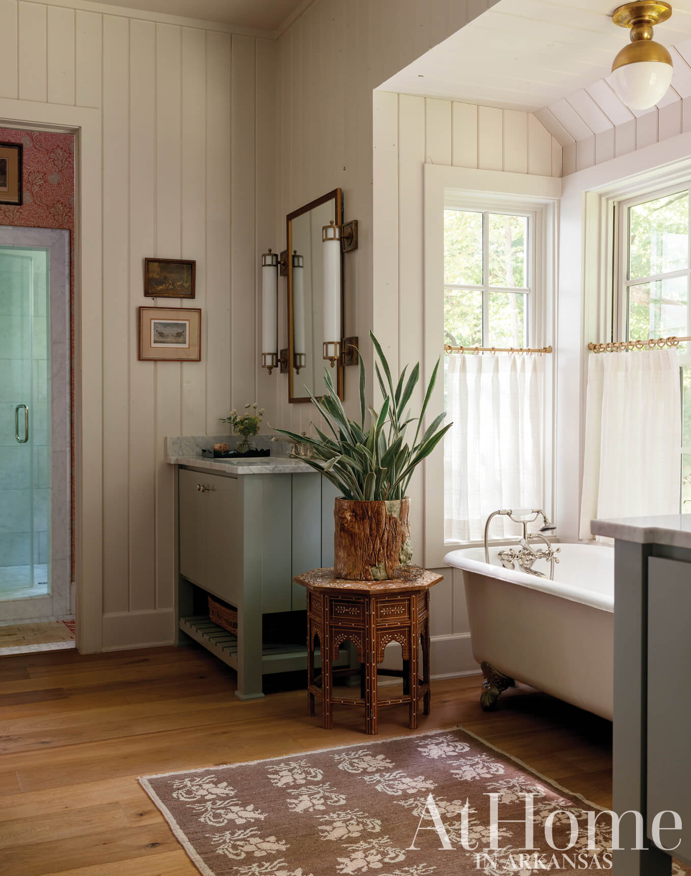 White bathroom with a vintage tub, marble sink, and wood flooring.