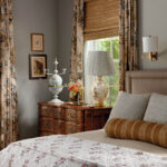 Bedroom corner with a large bed, curtains, and a dresser.