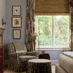 Blue and patterned armchair in a bedroom with a large window and curtains.