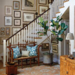 Wooden bench with blue pillows, artwork, and a fiddle-leaf fig plant.